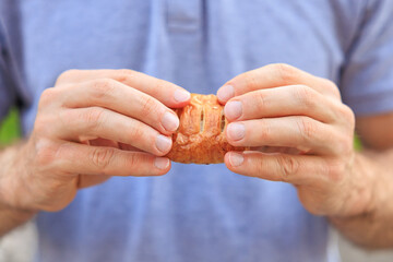 A man's hand holds a mini puff pastry with cheese, snack and fast food concept. Selective focus on hands