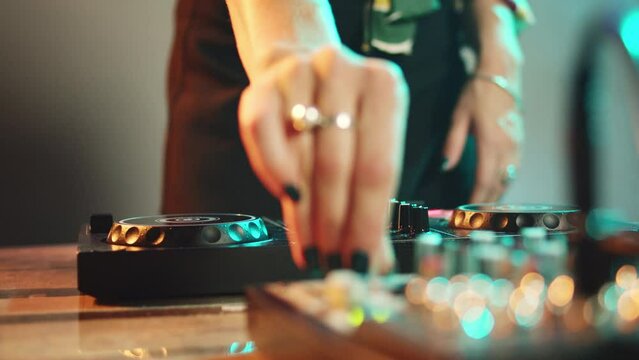 Young performer using dj electronics and headset to mix techno music and play remix songs on turntables, having fun at nightclub. Woman with crazy makeup mixing instruments. Close up. Handheld shot.