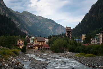 View of Dombai ski resort on the banks of the Amanauz River at the foot of the mountains of the North Caucasus on a summer day, Karachay-Cherkessia, Russia