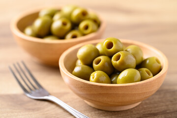 Pickled olives, Pitted green olives in wooden bowl - obrazy, fototapety, plakaty