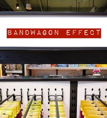 Store product shelf with tag written BANDWAGON EFFECT refers to psychological phenomenon tendency...