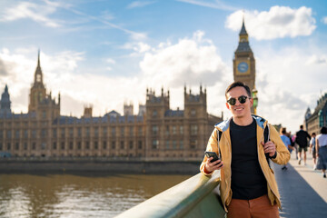 Young happy Latin man tourist wearing sunglasses and casual outfit holding smartphone while...