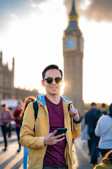 Young cheerful Latin man tourist wearing sunglasses and casual outfit holding smartphone while...