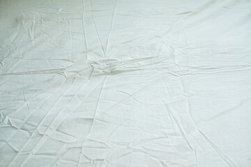 Light yellow soft wrinkled fabric background on bed. Light fabric