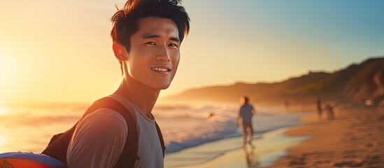 Asian male model in his 20s, surfing with a surfboard at sunset beach, embracing the adventurous lifestyle of outdoor water sports in summer.