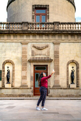 Fototapeta na wymiar Happy young smiling Latin woman tourist in casual clothes and sunglasses taking selfie with smartphone while standing against blurred historic Chapultepec Castle in Mexico City during trip
