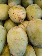 Close up pile of tasty fresh mangoes sold at the market as a background.