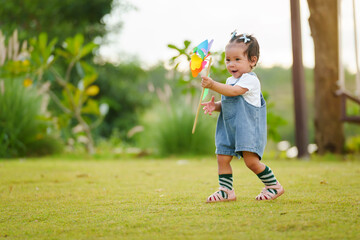 infant baby playing and walking first step on green grass in park