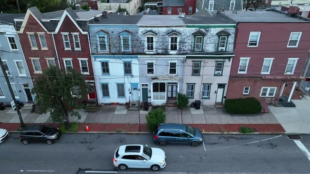 Row houses in American city. Aerial truck shot of inner city urban housing in USA. Traffic on one way street. Cinematic drone shot.