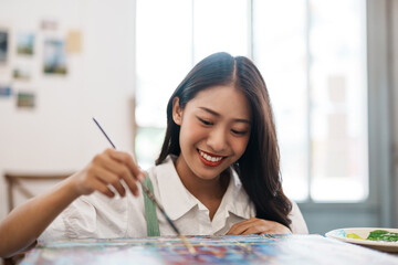 Cheerful young asian woman artist smiling drawing at art studio.