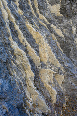 Swirling color in light and dark in a natural rock formation, cream colored and dark gray, as a nature background
