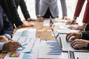 A group of business people are meeting to analyze data for a marketing plan. Office workers work in a team meeting with project planning documents on the conference table. Close-up pictures
