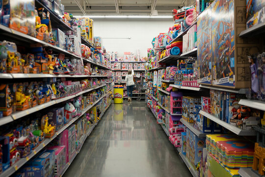 Tigard, OR, USA - Dec 5, 2023: A shopper chooses a doll on the shelf at the toys section in a Walmart Supercenter in Tigard, Oregon, during holiday shopping season.