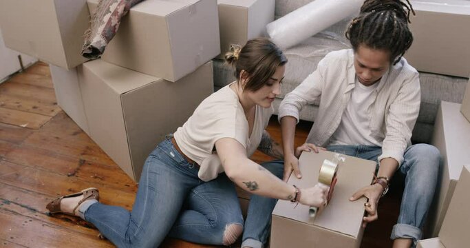 Happy couple, tape and box for moving house, relocation or new home in property or real estate. Man and woman packing boxes for renovation, investment or packaging equipment on living room floor