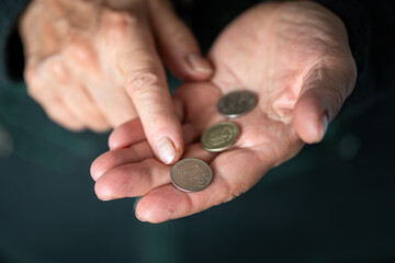 Elderly woman counts a coins, wrinkled female hands with metal money closeup. Concept of poverty,...