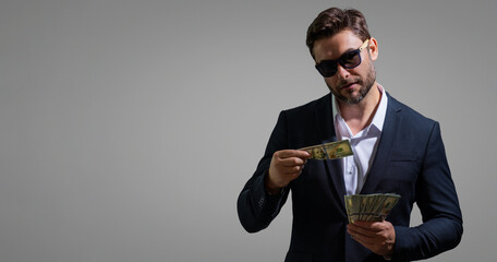 Man holding cash money in dollar banknotes on isolated gray background. Studio portrait of...