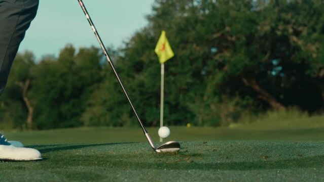 Golfer hitting chip shot towards pin in extreme slow motion, telephoto close up golf shot in 4k
