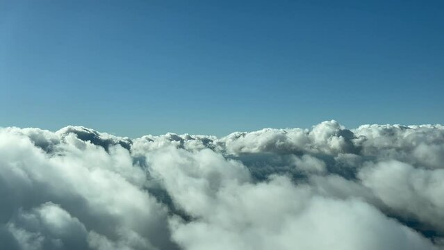 Flying across a clouded sky with some fluffy clouds, as seen by the pilots. Splendid, bright and sunny winter morning. 1000om high.