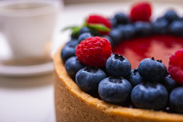 fresh blueberries and raspberries and mint leaves decorated cheesecake close-up. Confectionery, baking, bright colors