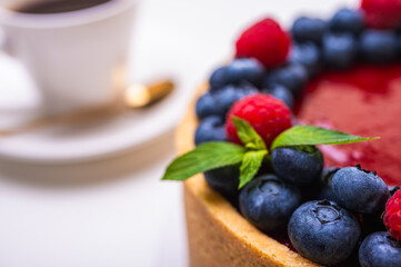 close-up of cheesecake decorated with fresh berries, blueberries and raspberries and mint leaves. confectionery, baking, bright colors