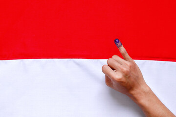Man's little finger after voting on Indonesia's presidential election against Indonesia flag
