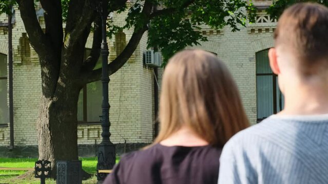 Tall student insults young man in street.Young lady stands for guy in glasses. Woman with long hair pushes aggressive student in campus park