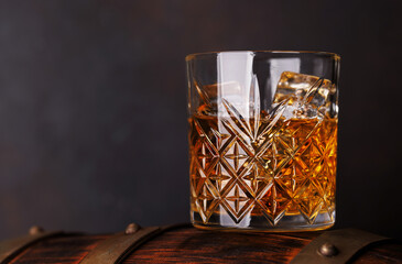 Whiskey glass with ice on a rustic barrel, a classic sip
