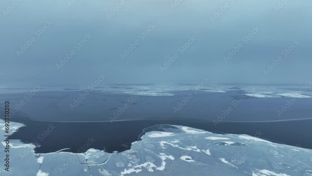 Poster Panoramic view of a large lake. The water has not yet frozen in the middle, and a layer of ice has already formed on the edge of the lake.