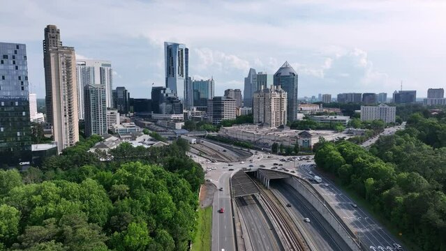 Cinematic aerial view of Buckhead Atlanta road traffic flow with skyline buildings in background, Georgia, USA