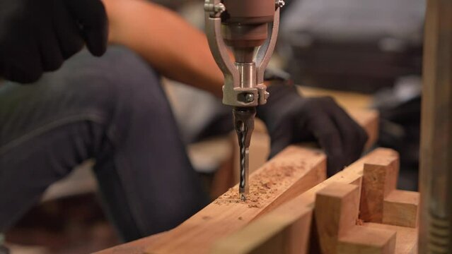 close up hands worker using drill machine on timber to drill the mold. finishing woodworking internal timber surface on lathe drill machine with flying Sawdust.