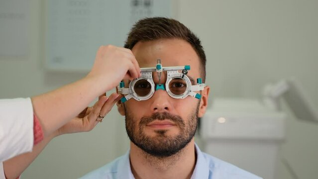 Optometrist or ophthalmologist uses phoropter ocular device tool to measure vision diopters of a man with retina defects