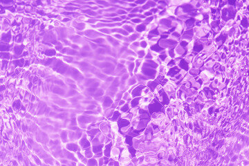 Purple water bubbles on the surface ripples. Defocus blurred transparent purple colored clear calm water surface texture with splash and bubbles. Water waves with shining pattern texture background