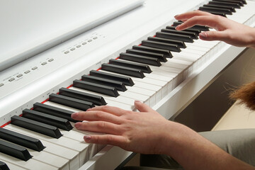 Close-up of a young woman's hands playing an electronic piano.
