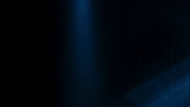 Abstract dark background with blue cold flashing light beam spot and laser illuminate falling rain and smoke. Vertical beams and multiple lasers flashing on all directions.