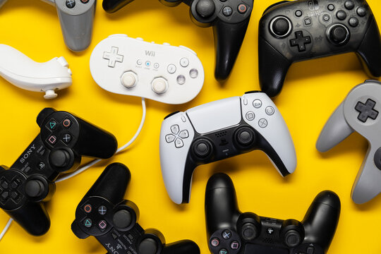 Verschiedene Generationen Gamecontroller der Playstation und Nintendo Spielekonsolen, vor einfarbig gelben Hintergrund, top view