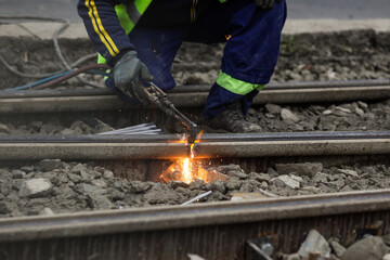 Details with a worker using an oxy-acetylene torch to cut metal tramway tracks.