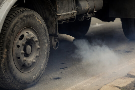 Details with the exhaust pipe of an old truck producing heavy smoke.