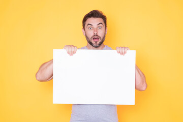 Surprised funny man holds the white sign, blank card. Placard ready for your product. Sign to your...