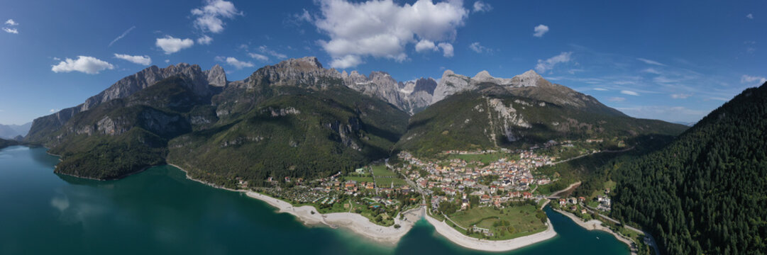The Improbable aerial landscape of village Molveno. Aerial view of Lake Molveno, north of Italy in the background the city of Molveno, Alps, blue sky, campanile basso, cima tosa Italian dolomites.