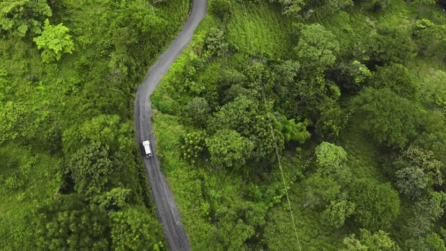aerial of 4x4 jeep touring car driving off road crossing jungle green deep vegetation exploring Costa Rica 