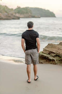 Man in thirties strolls coastal Dominican beach, serene view