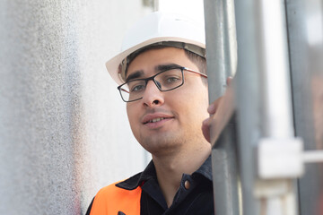 technician male with helmet standing near a building