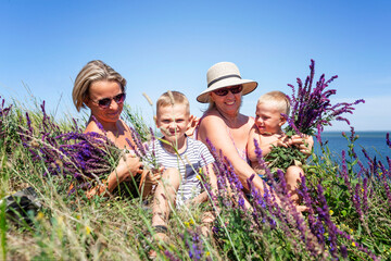 Women with children collect sage in the field. A young woman, a grandmother in a lilac sundress and...