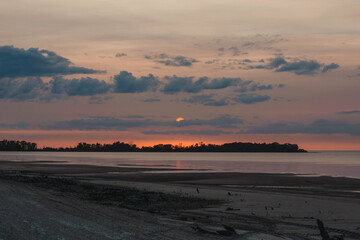 Beach sunset with blue clouds and setting sun