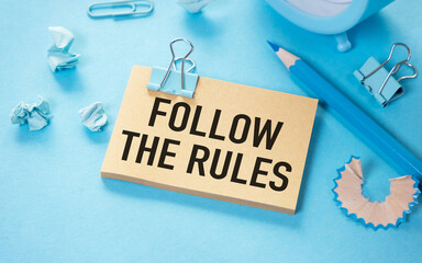 Follow The Rules text written on a notebook with blue pen