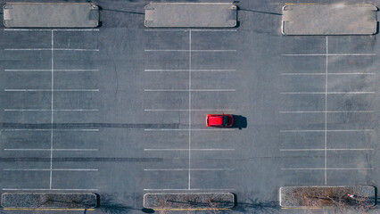 A red car is standing alone in the parking lot