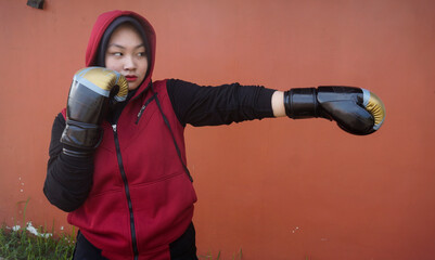 Asian muslim girl boxer wearing hijab and boxing gloves making puch in training © Hendra Fauzy