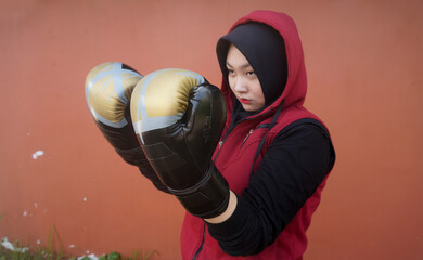 Asian muslim girl wearing hijab and boxing gloves ready to kickboxing training