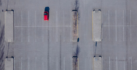 A red car is parked in an empty parking lot