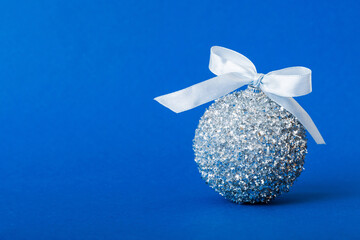 Christmas ball on colored background. decoration bauble with ribbon bow with copy space